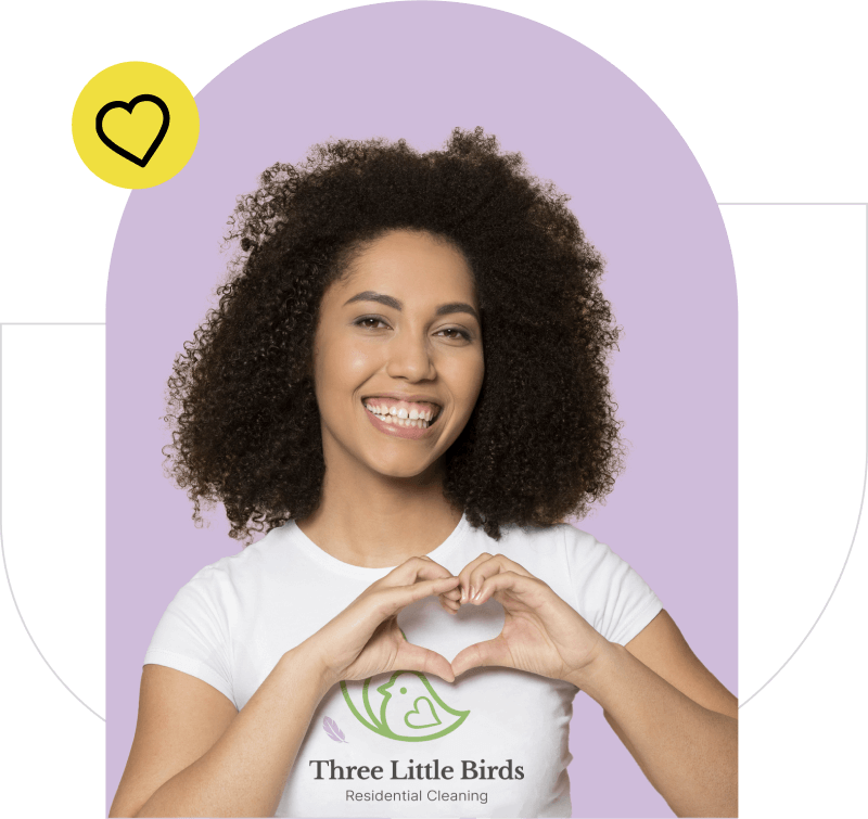 Smiling woman wearing a 3 Little Birds T-shirt, making a heart with her hands